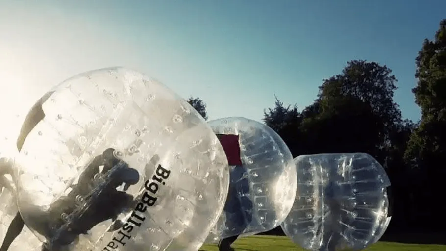 People in inflatable balls playing outdoors.