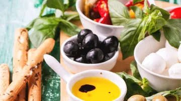 Mediterrane Snacks mit Oliven und Grissini auf Tisch.