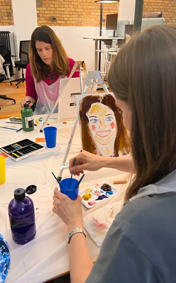 Women painting portraits in art studio.