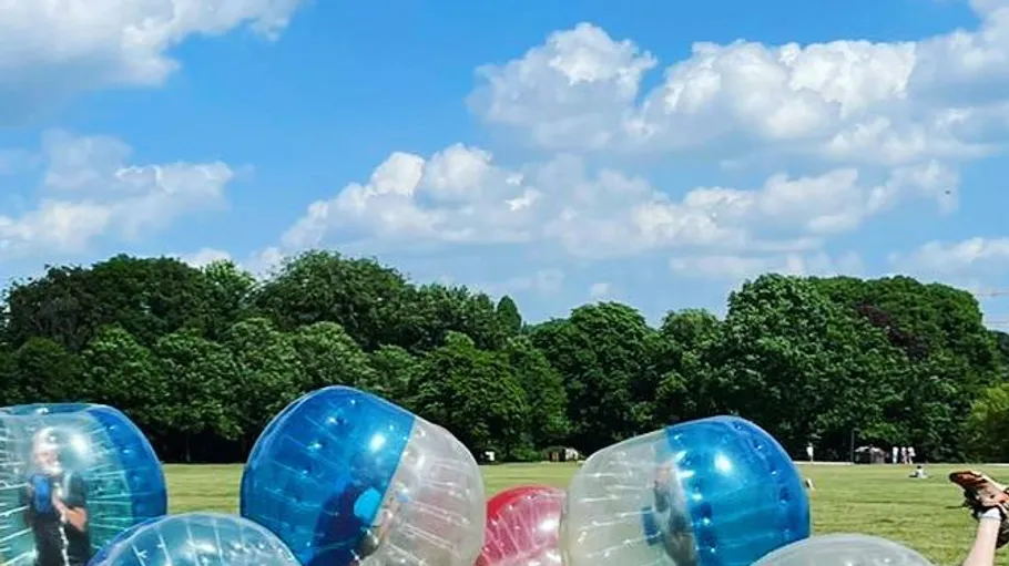 People playing in giant bubbles on grassy field.