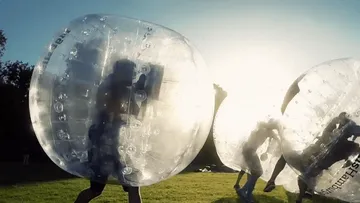 People in inflatable balls playing outdoors.