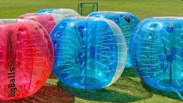 Inflatable zorb balls on grassy field.