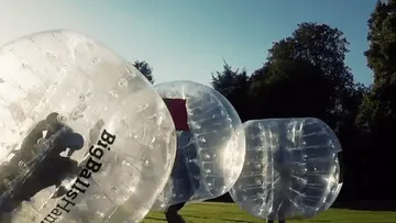Leute spielen in aufblasbaren Bällen im Freien.