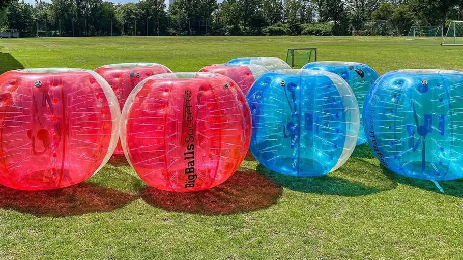 Inflatable red and blue balls on grass field.