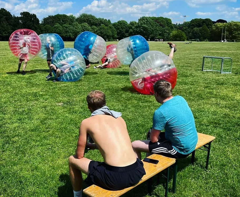 People playing bubble ball on grassy field.