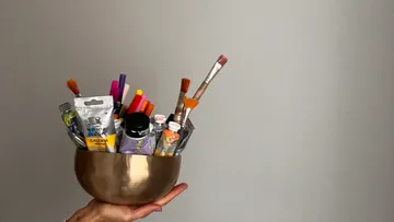 Hand hält Schüssel mit Kunstbedarf.