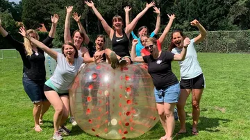 Group celebrating outdoors with a bubble ball.