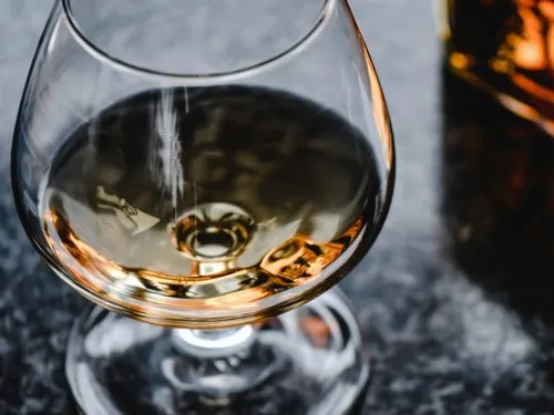 Ein Glas mit Flüssigkeit steht auf einer Oberfläche.