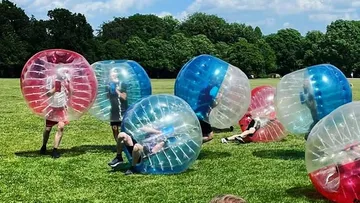 People in inflatable balls on a field.