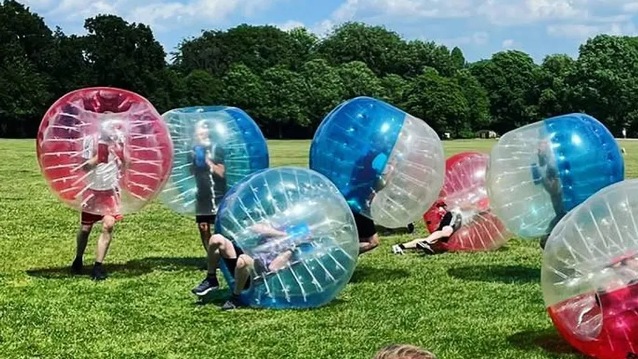People in inflatable balls on a field.