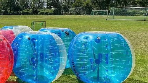 Inflatable bumper balls on a grassy field.