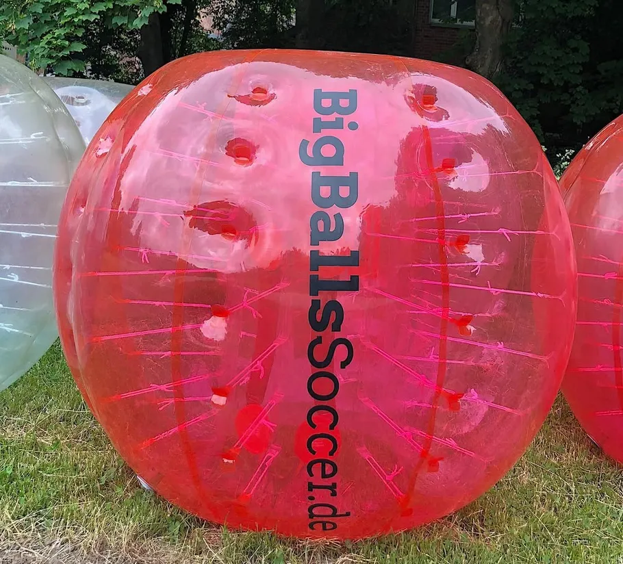 Large red inflatable ball on grass.