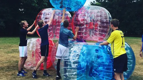 People stacking inflatable balls in a field.
