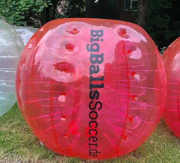 Red inflatable ball on grass outdoors.