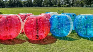 Bunte aufblasbare Bälle auf einem Rasenfeld.