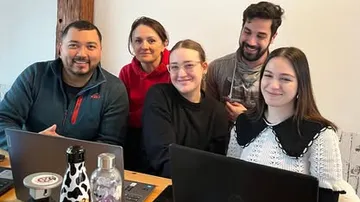 Group smiling around laptops in a room.