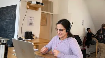 Woman with headset on laptop in office.