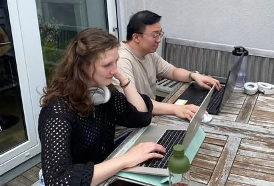 Zwei Personen arbeiten draußen an Laptops.