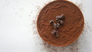 Schokoladendessert mit Kakaopulver auf weißer Oberfläche.