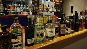 Verschiedene Spirituosenflaschen auf einer Bar aufgereiht.