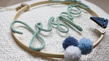 Yarn name art on textured fabric surface.