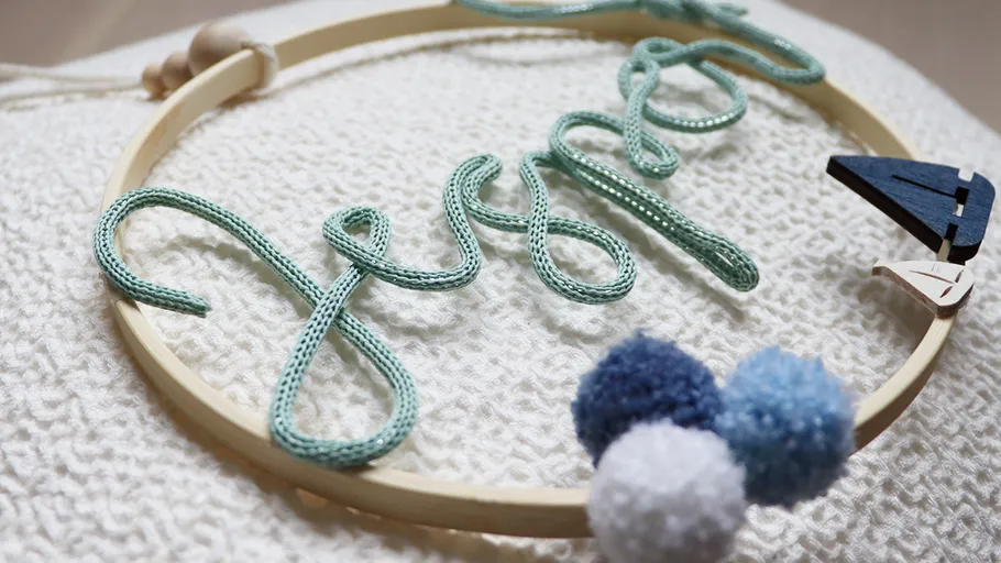 Yarn name art on textured fabric surface.