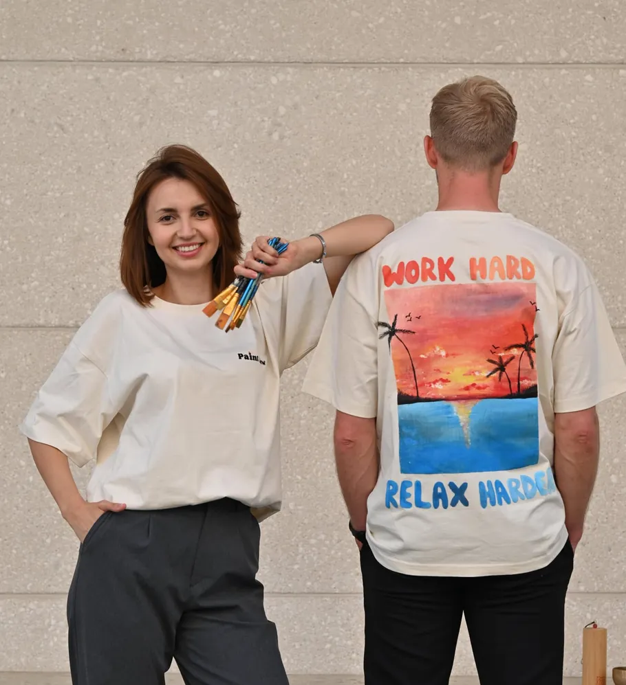 Frau mit Pinseln, Mann im Sonnenuntergangs-Shirt.