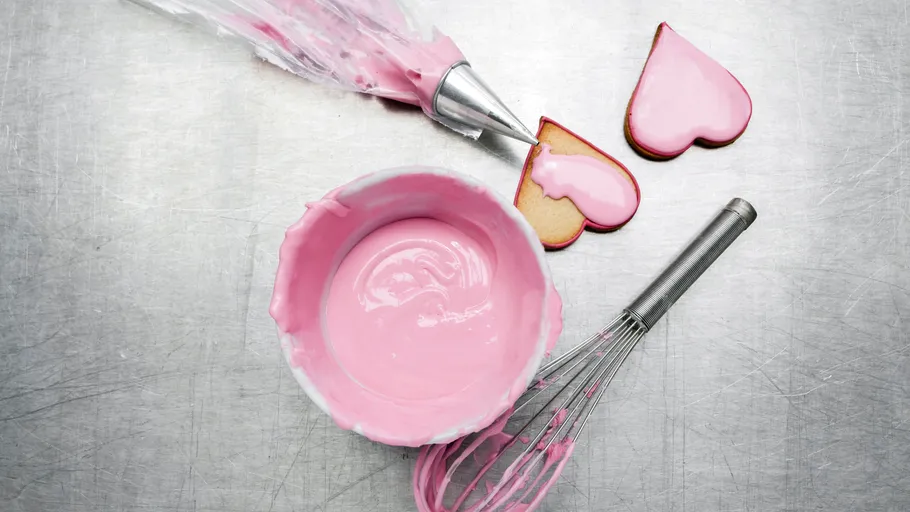 Herzplätzchen mit rosa Glasur auf Metalloberfläche.