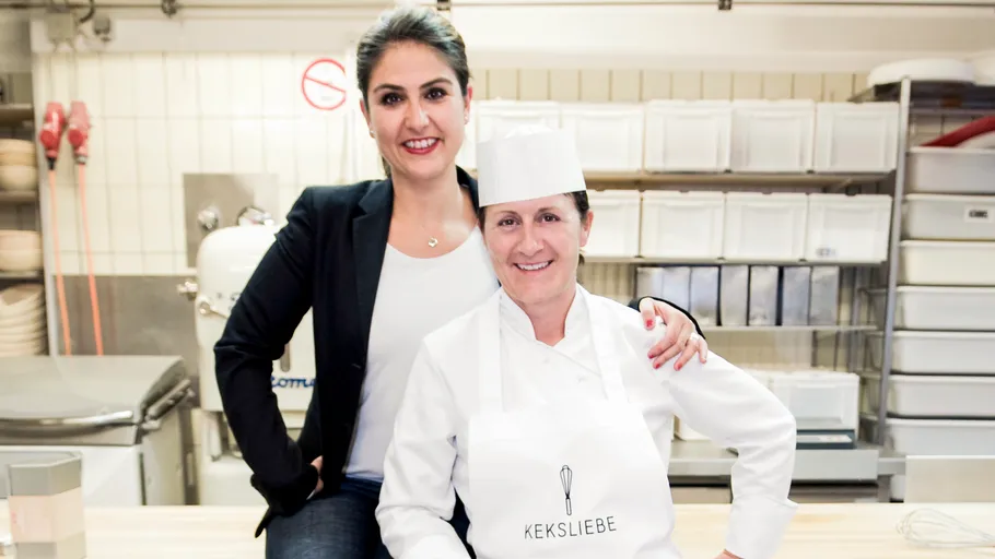 Two women smiling in a professional kitchen.