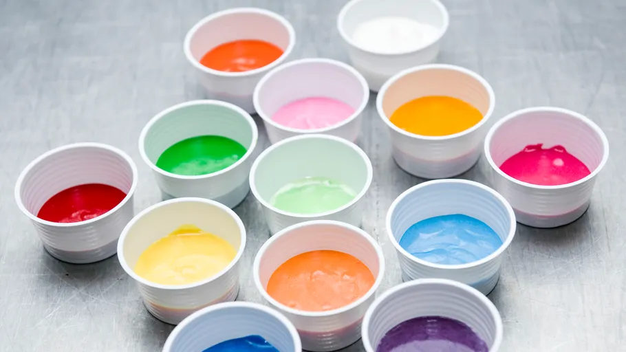 Colorful paints in cups on a metal surface.