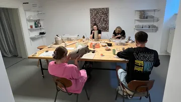Four people crafting clay sculptures in art studio.