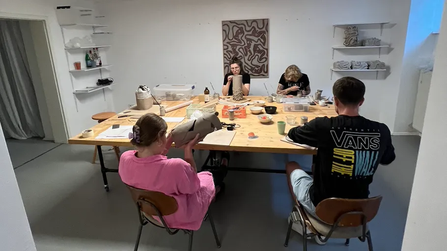 Vier Personen formen Tontöpfe in Kunststudio.