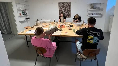 Personen basteln in einem Studio um einen Tisch.