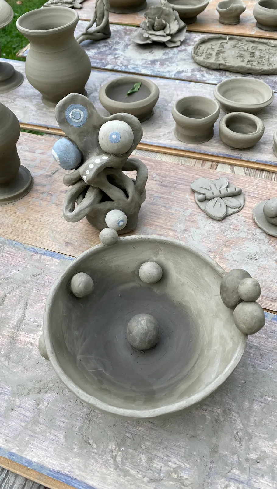 Clay sculptures and pots on wooden table.