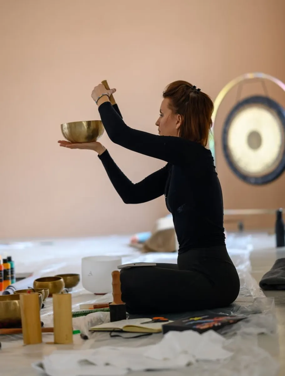 Person playing singing bowl in meditation room.