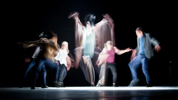Dancers moving on stage with blurred motion.