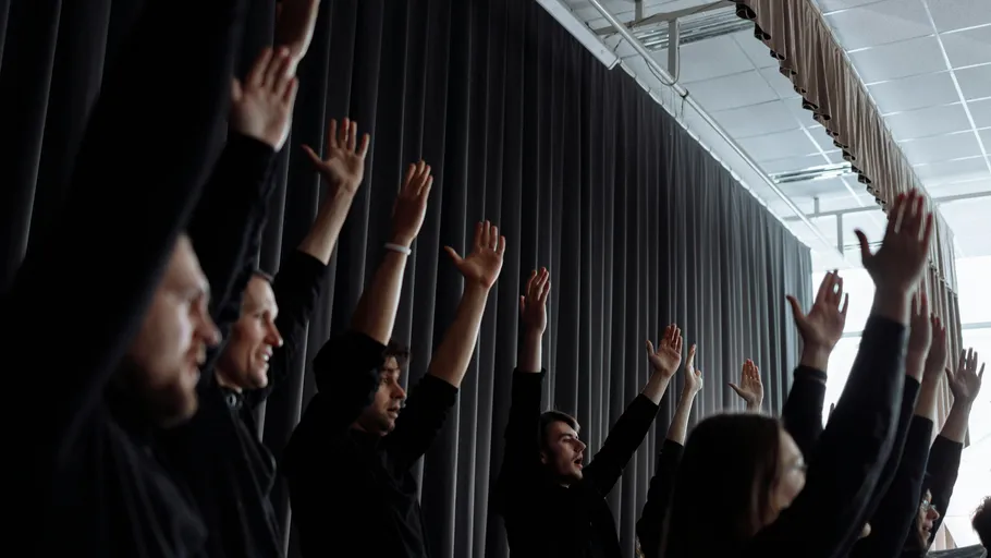 People raising hands in a dark room.