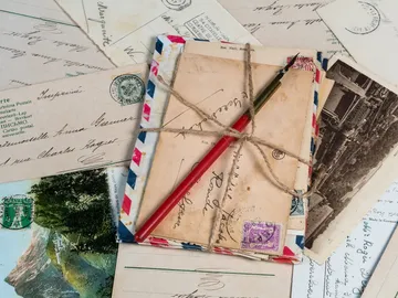 Bundle of letters and postcards with a pen.
