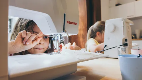 Children using sewing machines at home.