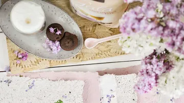 Tasse und Kekse mit Blumen auf Tisch.
