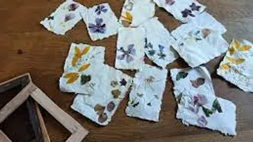 Handgeschöpftes Papier mit gepressten Blumen auf Tisch.
