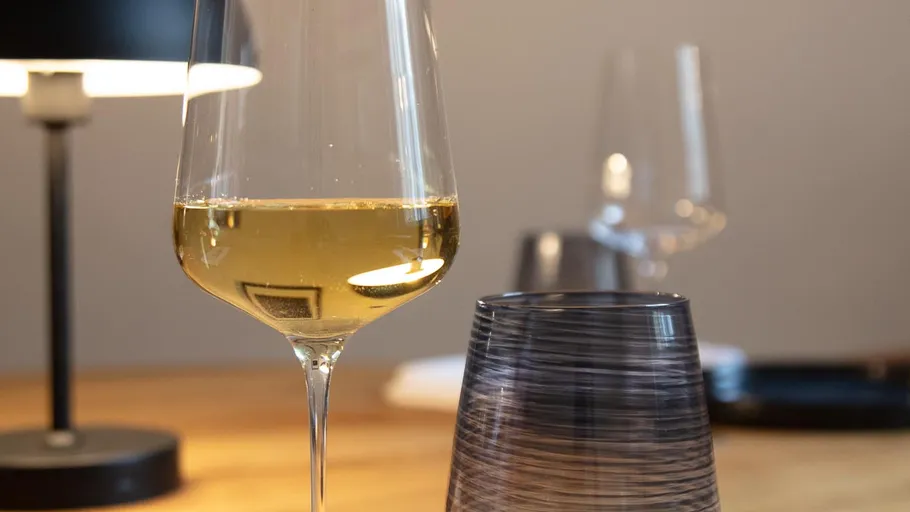 Wine glass and tumbler on a wooden table.
