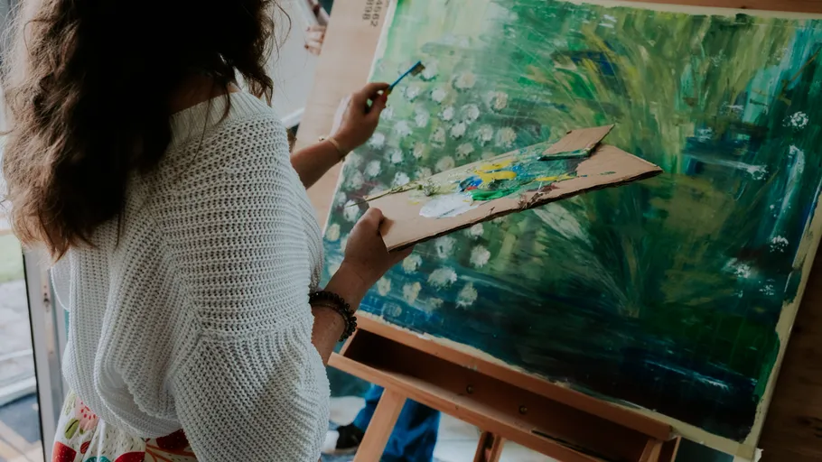 Woman painting on canvas in art studio.