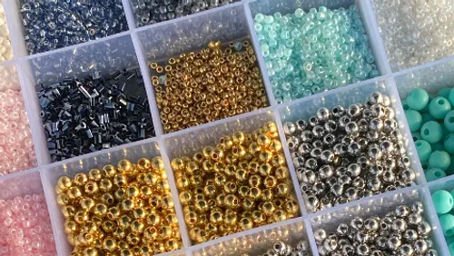 Assorted beads in a divided storage container.