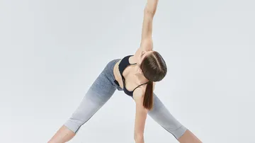 Frau dehnt sich in Yoga-Position drinnen.