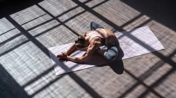 Frau praktiziert Yoga in sonnigem Raum.
