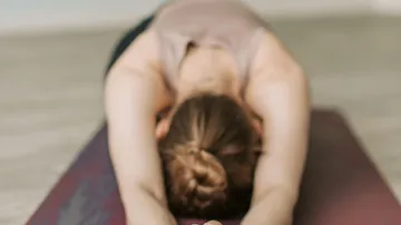 Frau macht Yoga-Kindhaltung drinnen.