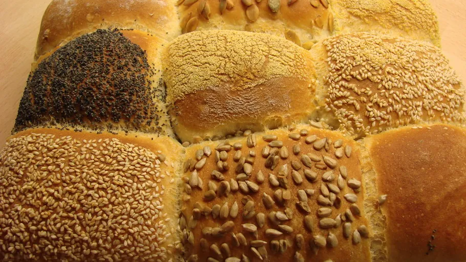 Assorted bread rolls with various seed toppings.