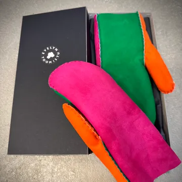 Bunte Fäustlinge neben schwarzer Geschenkbox.