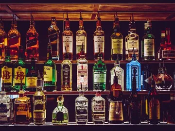 Shelf arranged with various bottles of alcoholic beverages.